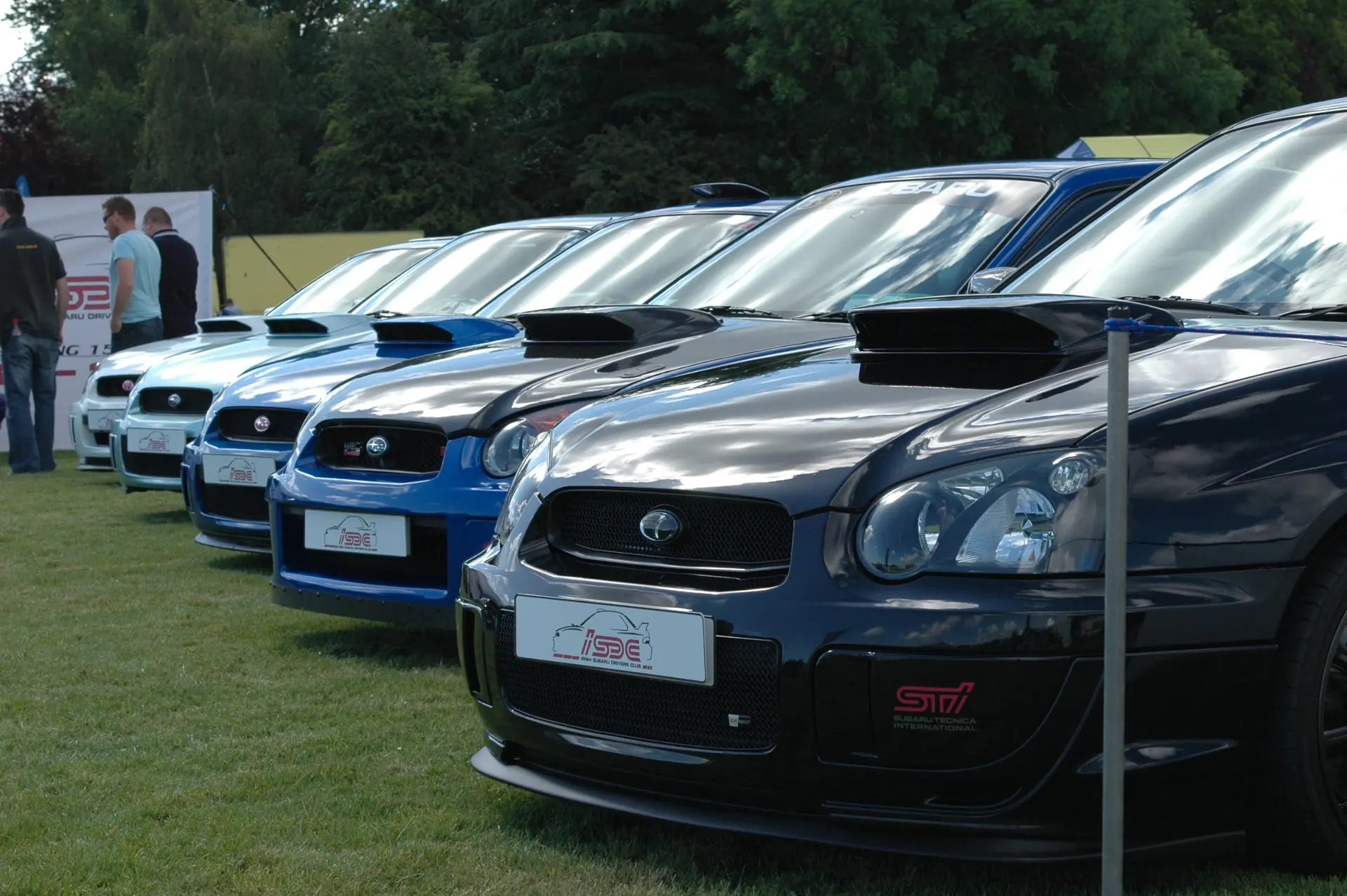A row of Subaru Imprezas with ISDC number plates on display at a club stand