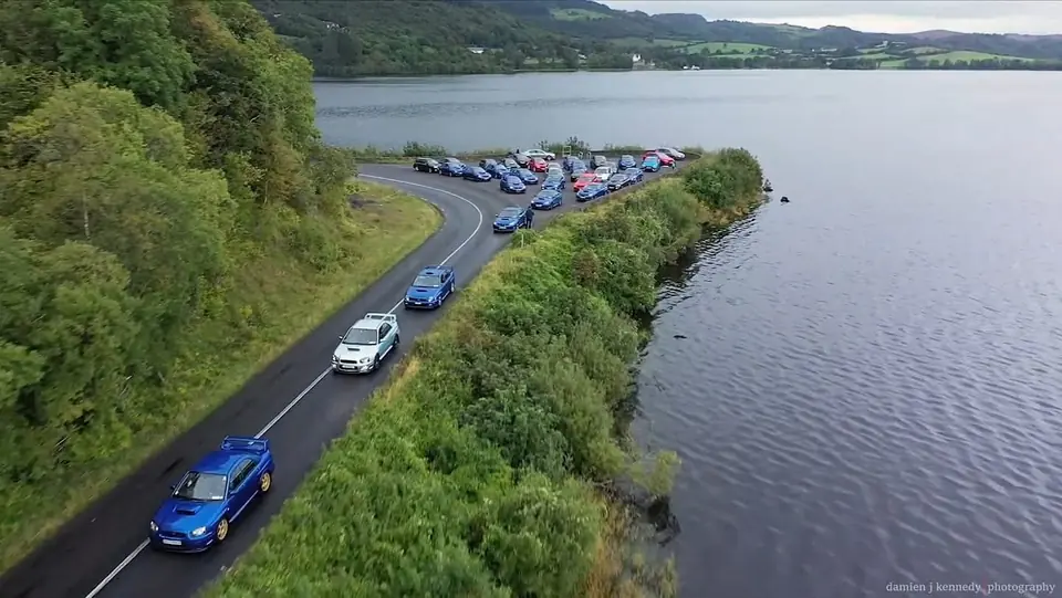Convoy of club cars along a lakeside road